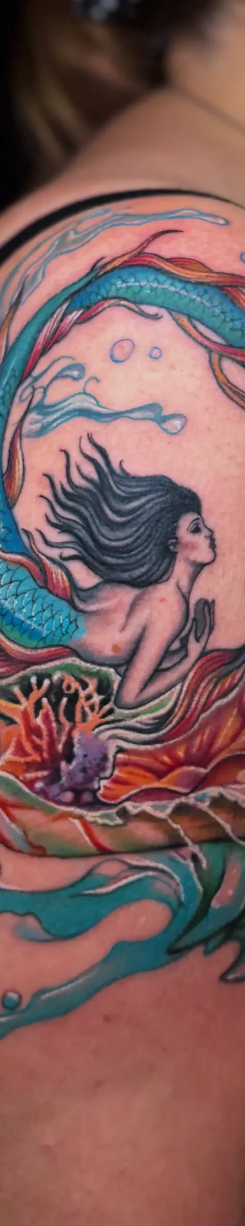 Realism style tattoo fix of an old mermaid design with vibrant new details.