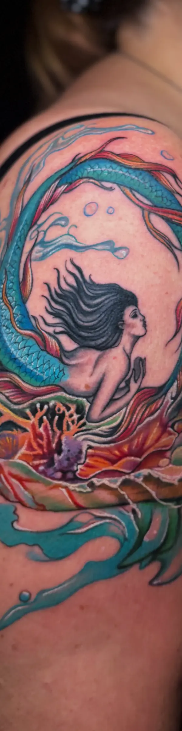 Realism style tattoo fix of an old mermaid design with vibrant new details.