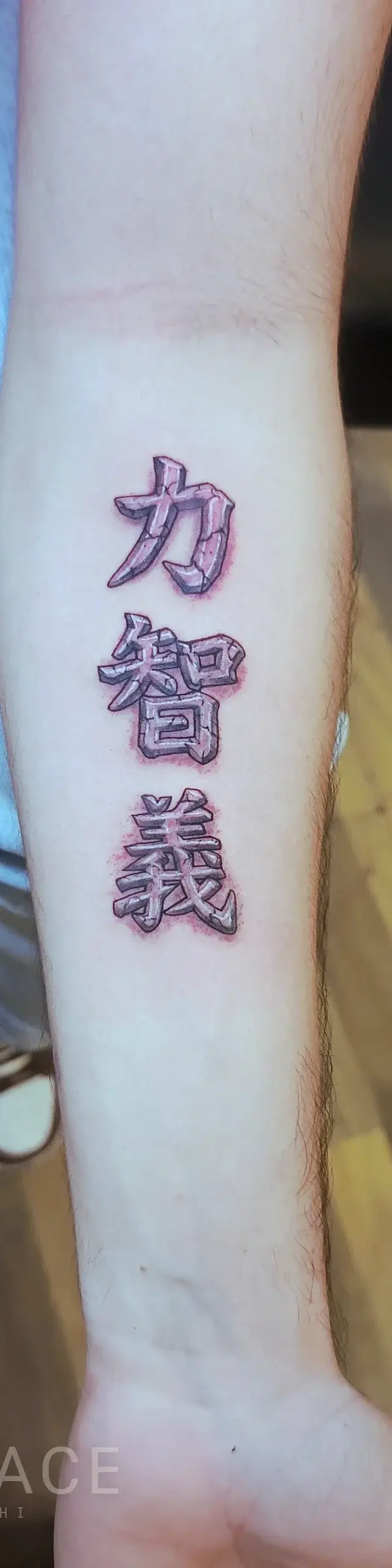 Close-up of a fine line Kanji symbol tattoo on a forearm, featuring delicate lines and precise execution.