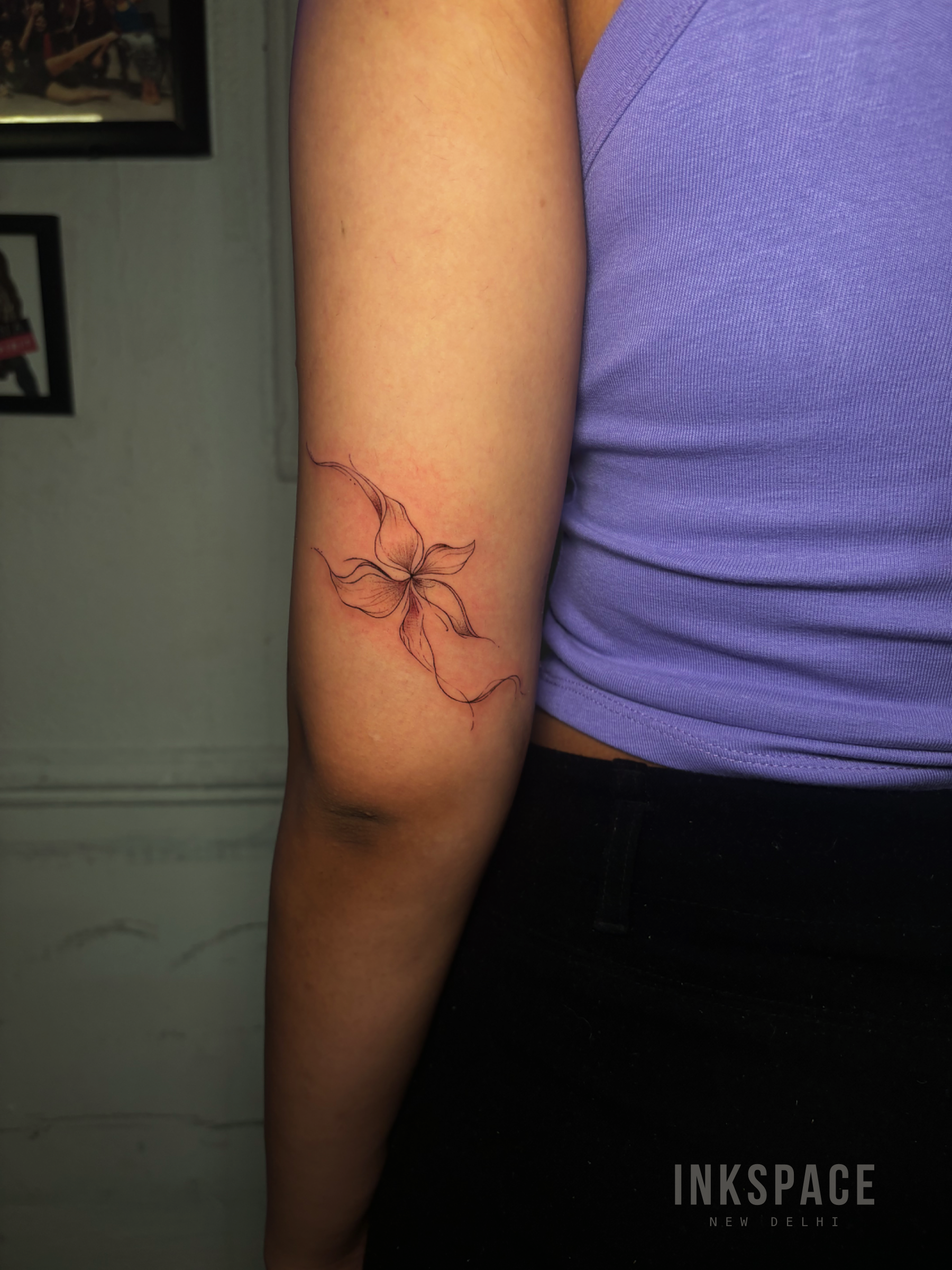Fine line Lilly tattoo on the back of arm by Bruna Freespirit at Inkspace