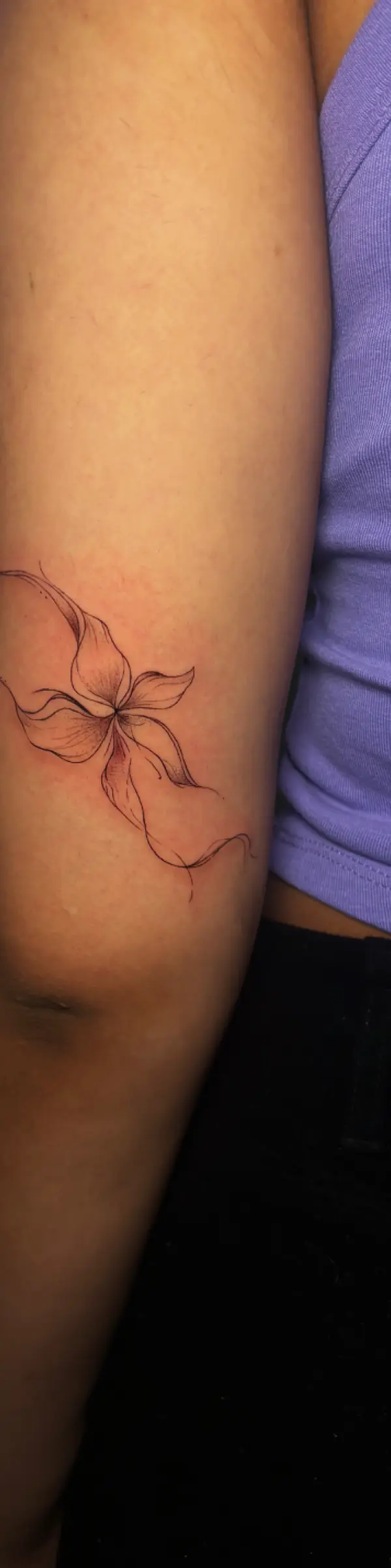 Fine line Lilly tattoo on the back of arm by Bruna Freespirit at Inkspace