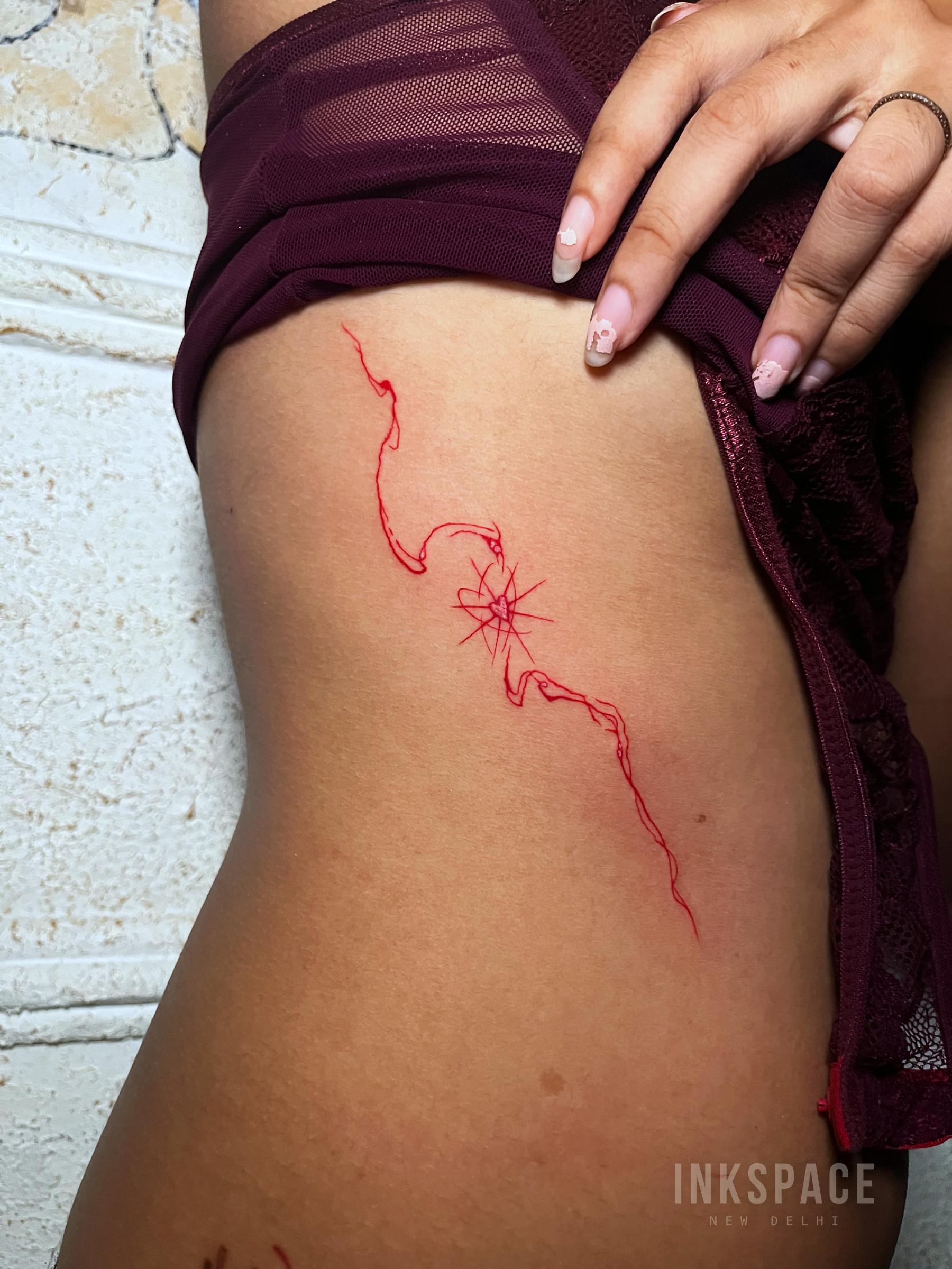 fine line tattoo featuring a single red design
