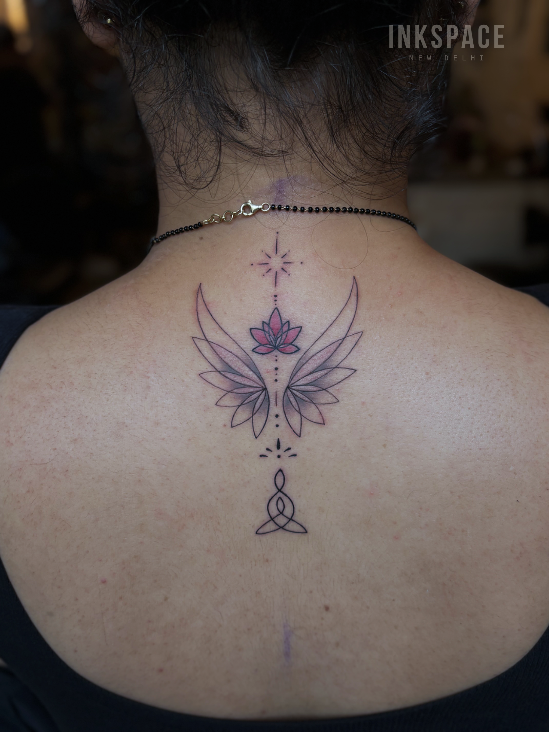 fine line tattoo of lotus flowers and wings